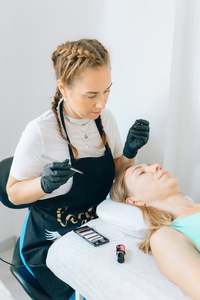 Makeup artist in gloves applying cosmetics to a client lying down.