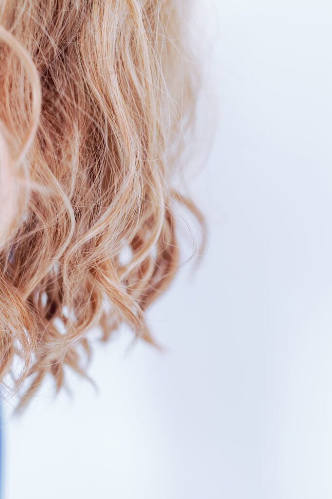 Detailed close-up of wavy blonde hair showcasing texture and style with a white background.
