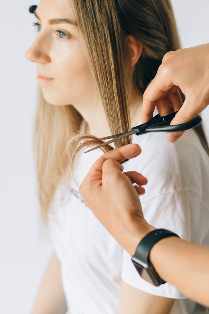 A stylist gives a precise haircut to a woman in a salon, focusing on self-care.